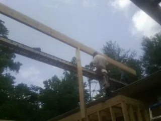 Carpenter setting a ridge beam over a new addition frame — Ice Dam Removal by Roofing Brothers in Wolflake