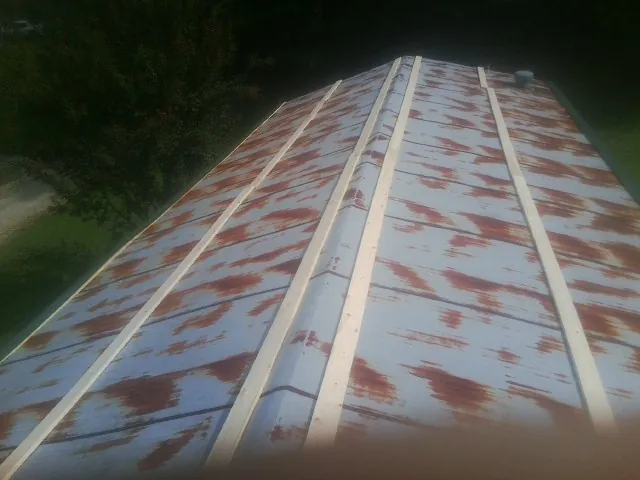Rusted metal roof panels with new wood purlins before replacement — Storm Damage Roof Repair in Wolflake by Roofing Brothers
