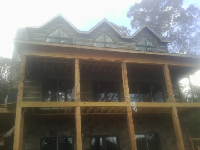 Dormers and porch framing on a large log home under construction — Roof Coating work by our crew in Wolflake