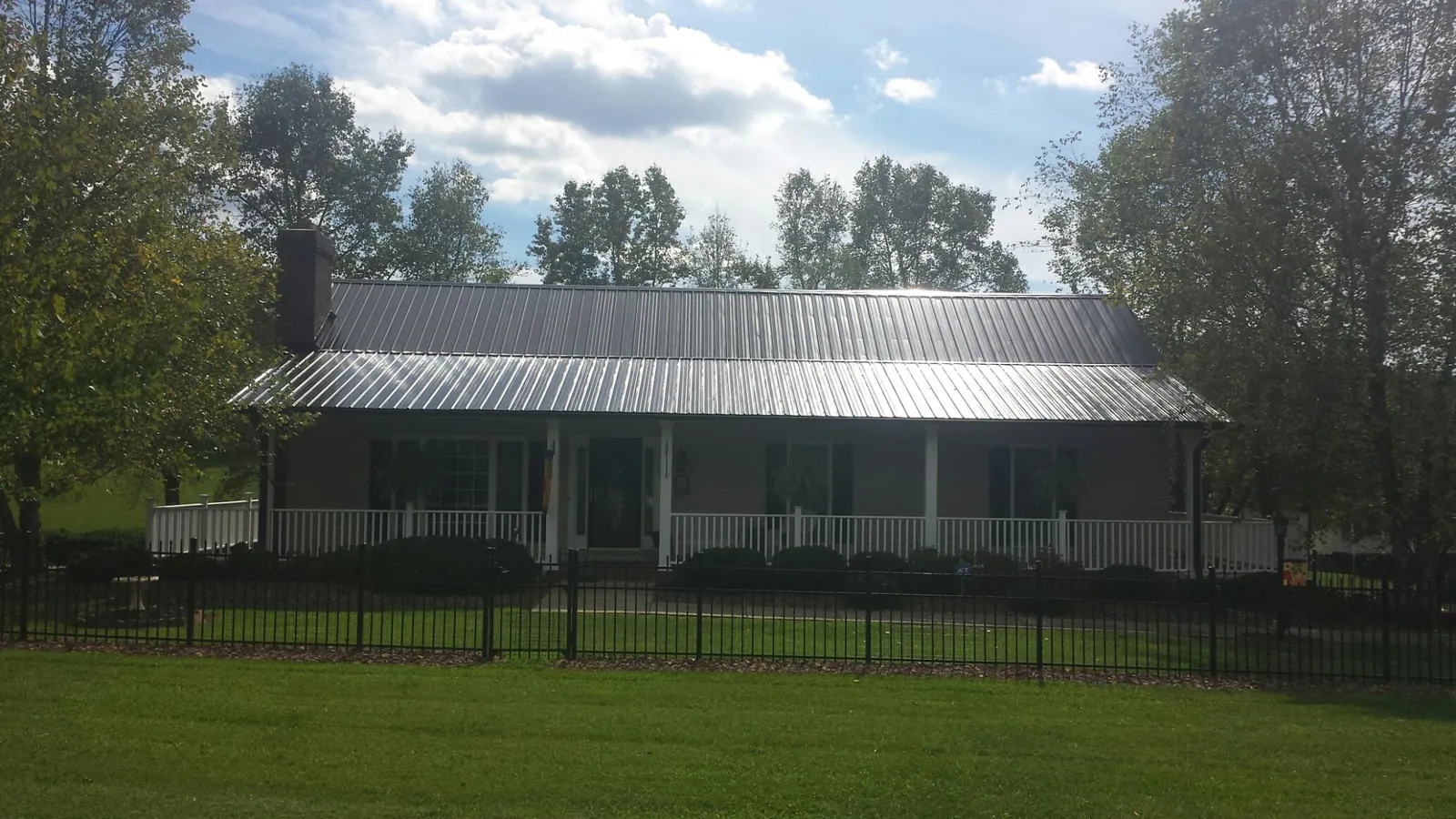 Gray metal roof on a brick ranch with a full width front porch — Gutter Guard Installation work by our crew in Wolflake