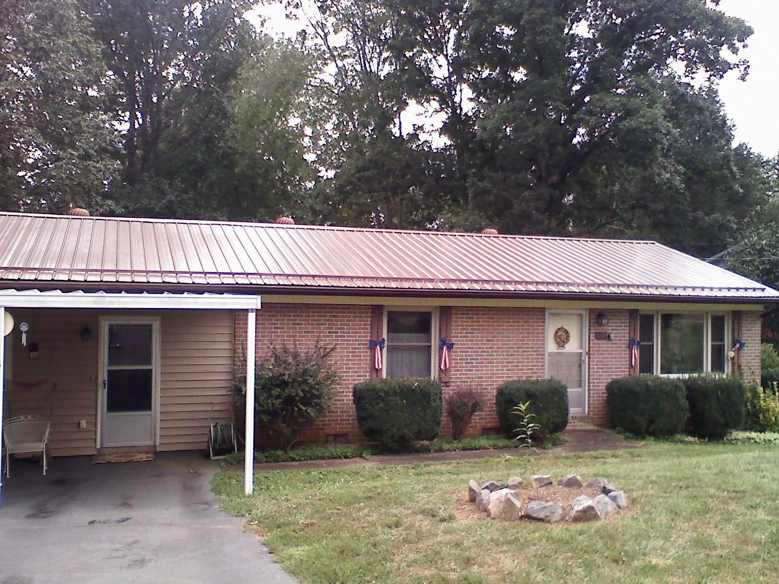 Bronze metal roof and carport on a brick ranch home — Roof Repair work by our crew in Wolflake