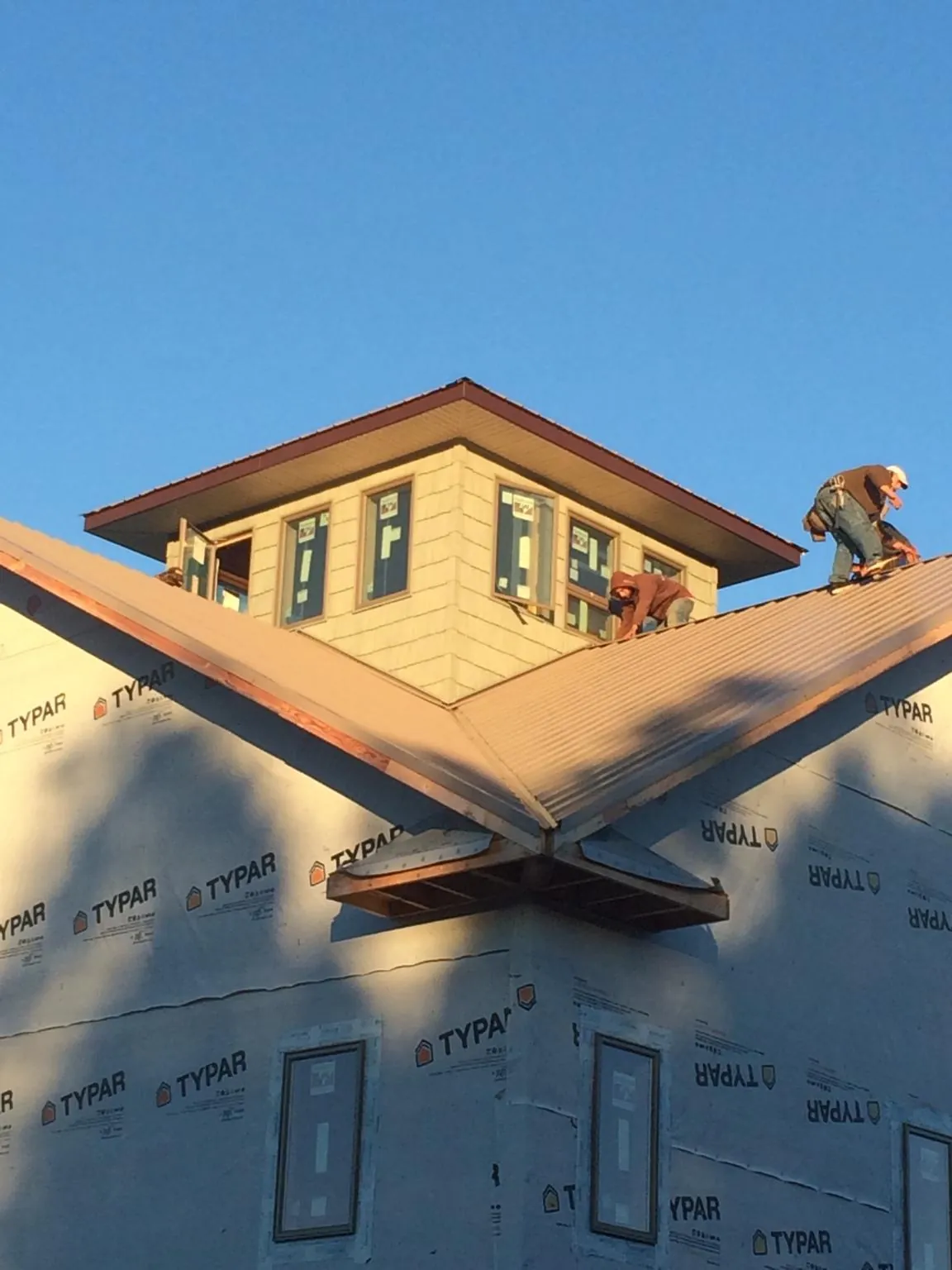 Roofers working around a rooftop cupola on a new metal roof at sunset — Roof Waterproofing in Wolflake by Roofing Brothers